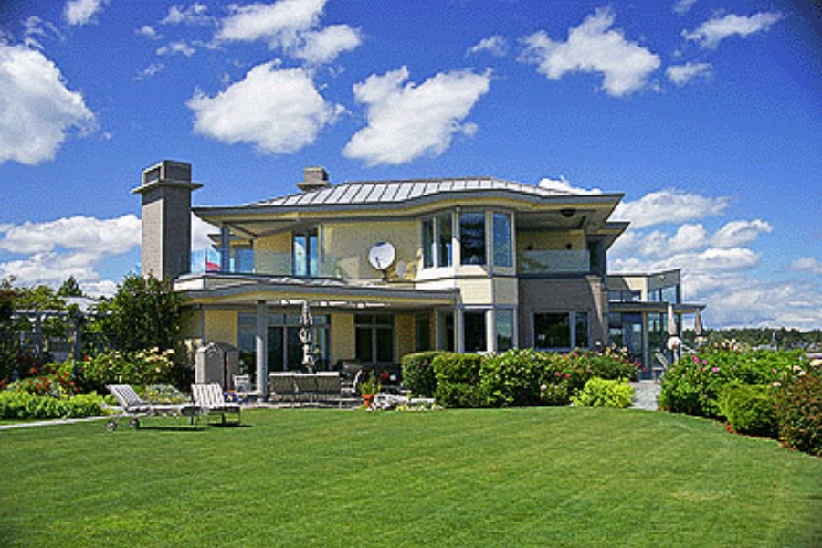 A large and contemporary residence at Humber Road with lighter colour siding and a large covered patio leading to a lawn.