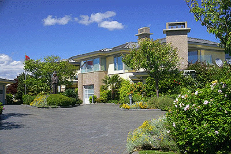 A large and contemporary residence at Humber Road with lighter colour siding and brick features with a stone driveway.