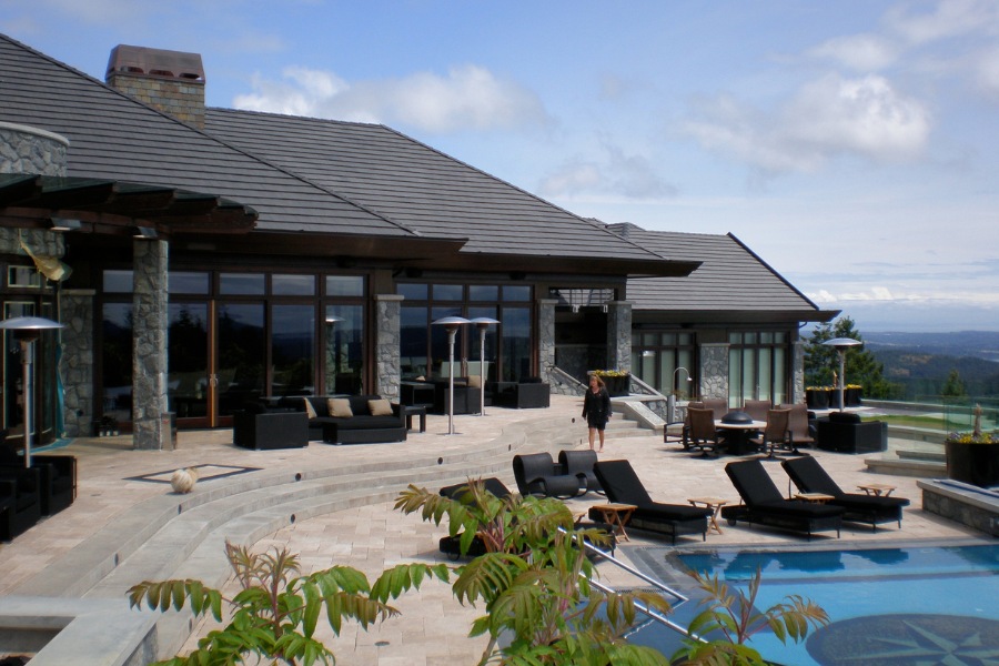 Contemporary Barrie Residence's backyard with a large stone patio, a beautifully tiled pool, outdoor seating, stone features, all overlooking a beautiful view.