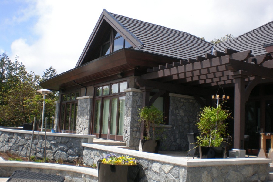 Contemporary Barrie Residence's backyard with a large stone patio, stone features, and an arbor.