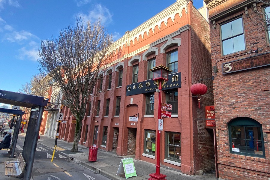 The exterior of Hook Sin Tong Building, a commercial property, designed by Alan Lowe Architecture with red and white stone exterior and brick features.