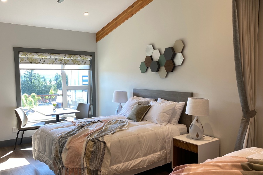 A bedroom with two beds and a window in the Qwalayu House, designed by Alan Lowe Architecture.