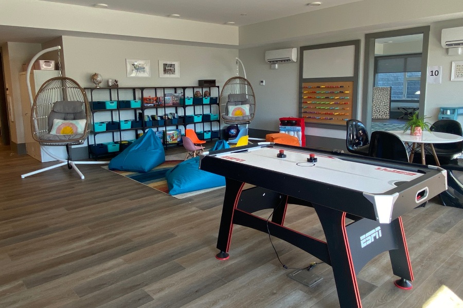 A game room with hanging hammock chairs, bean bags, and air hockey games in the Qwalayu House, designed by Alan Lowe Architecture.