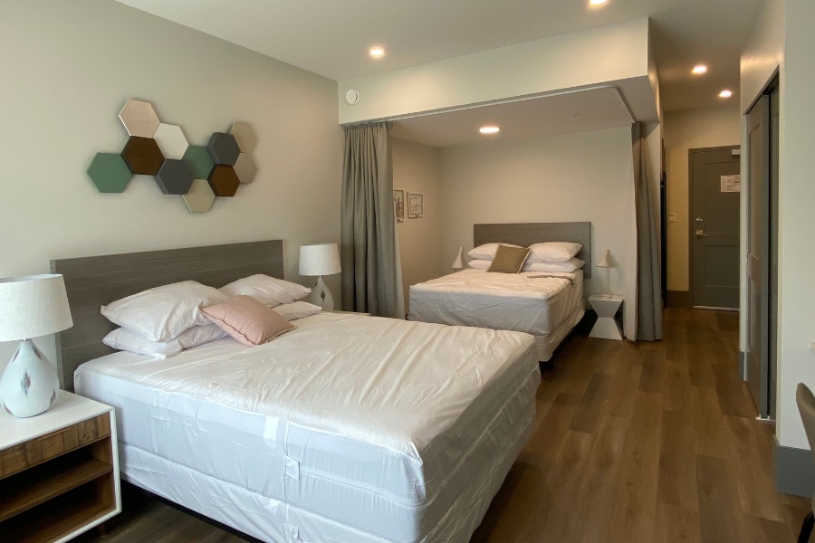 A bedroom with two beds and a window in the Qwalayu House, designed by Alan Lowe Architecture.