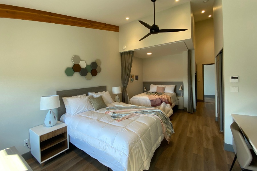 A bedroom with two beds and a window in the Qwalayu House, designed by Alan Lowe Architecture.