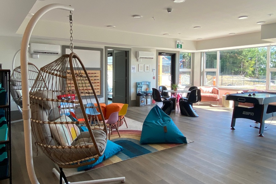 A game room with hanging hammock chairs, bean bags, and air hockey games in the Qwalayu House, designed by Alan Lowe Architecture.