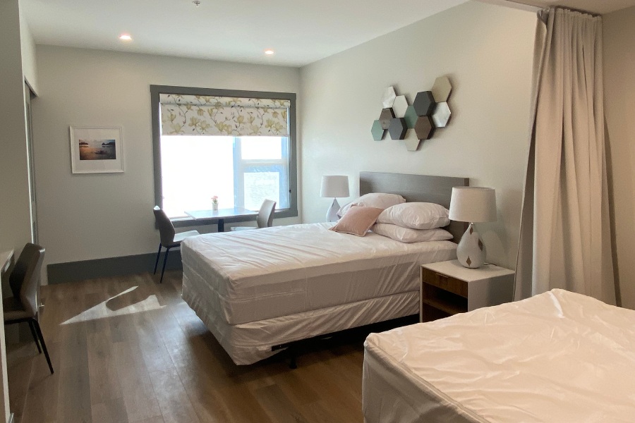 A bedroom with two beds and a window in the Qwalayu House, designed by Alan Lowe Architecture.